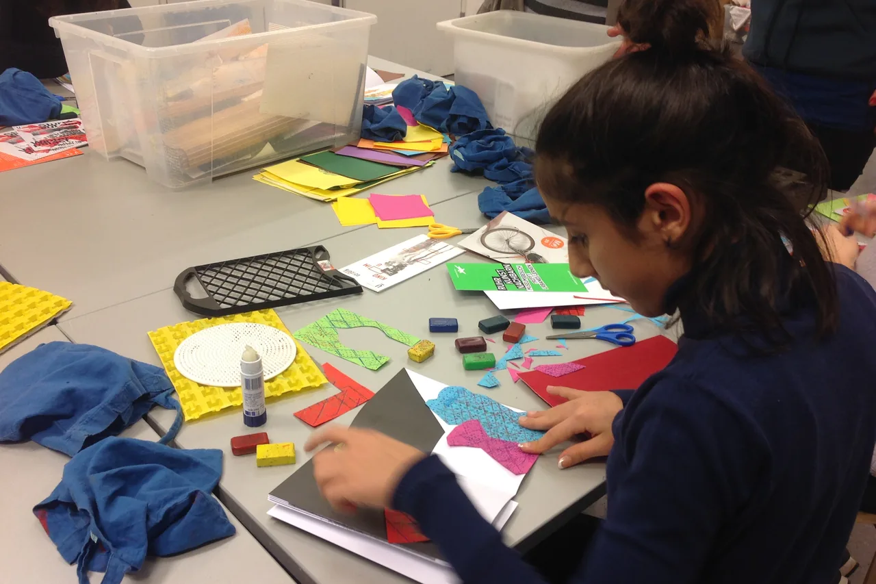 Student creating a collage from coloured paper in the creative workshop