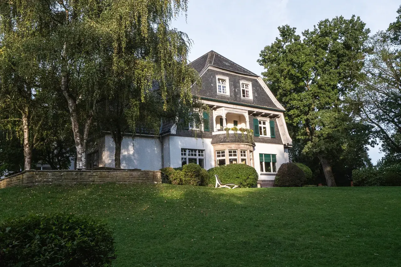 Villa Wewersbusch from outside: historic main house with lawn and old trees